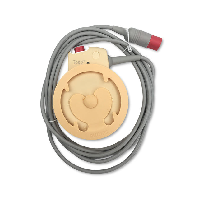 A fetal Toco transducer with a grey cable and red connector, primarily beige in color with the brand name 'Avalon' visible.